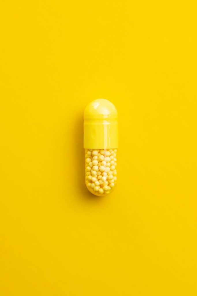 Vitamin capsule. Vitamin C pill on yellow background. Top view.